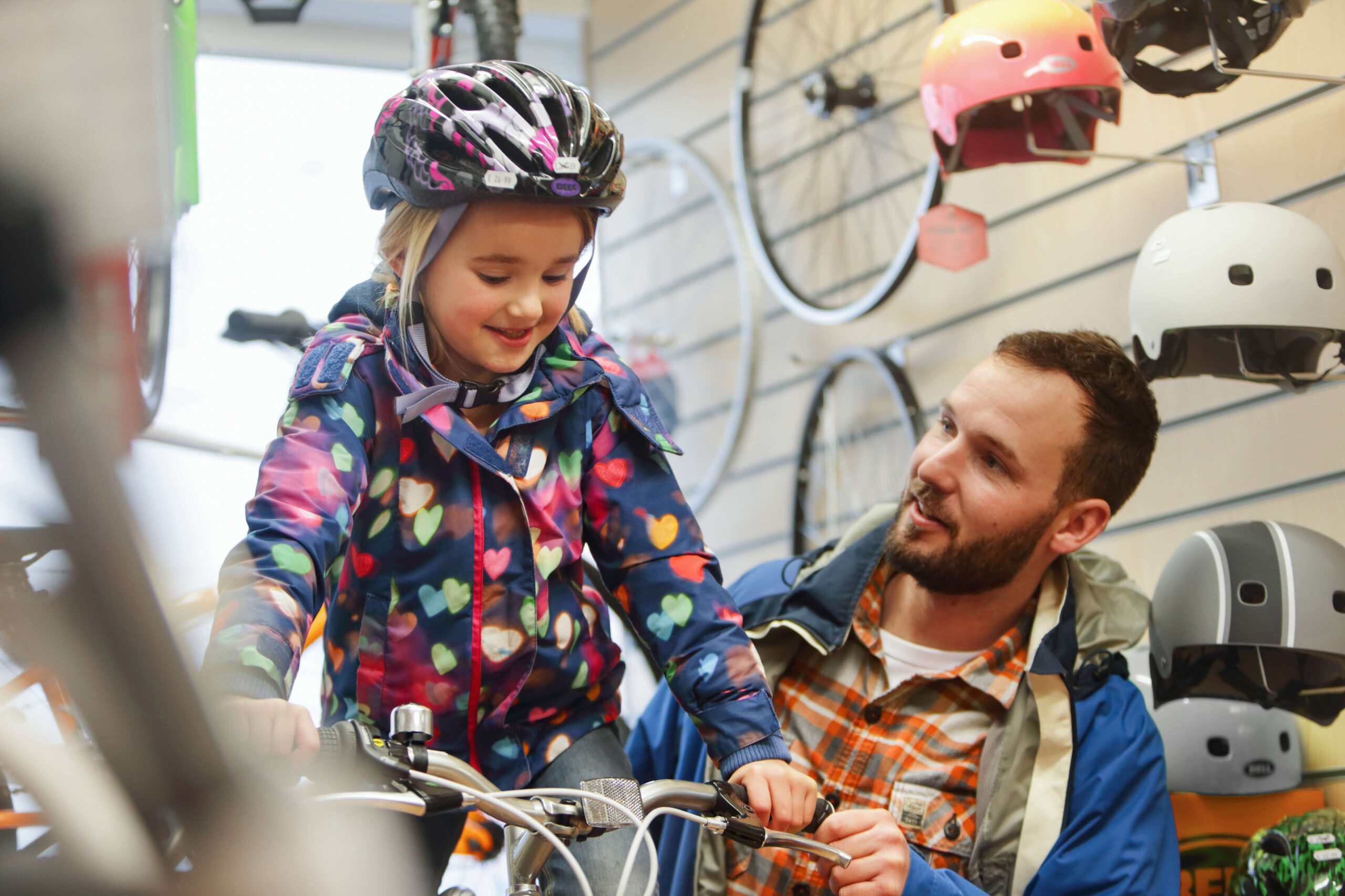 Child trying a new bike at a bicycle shop as father helps