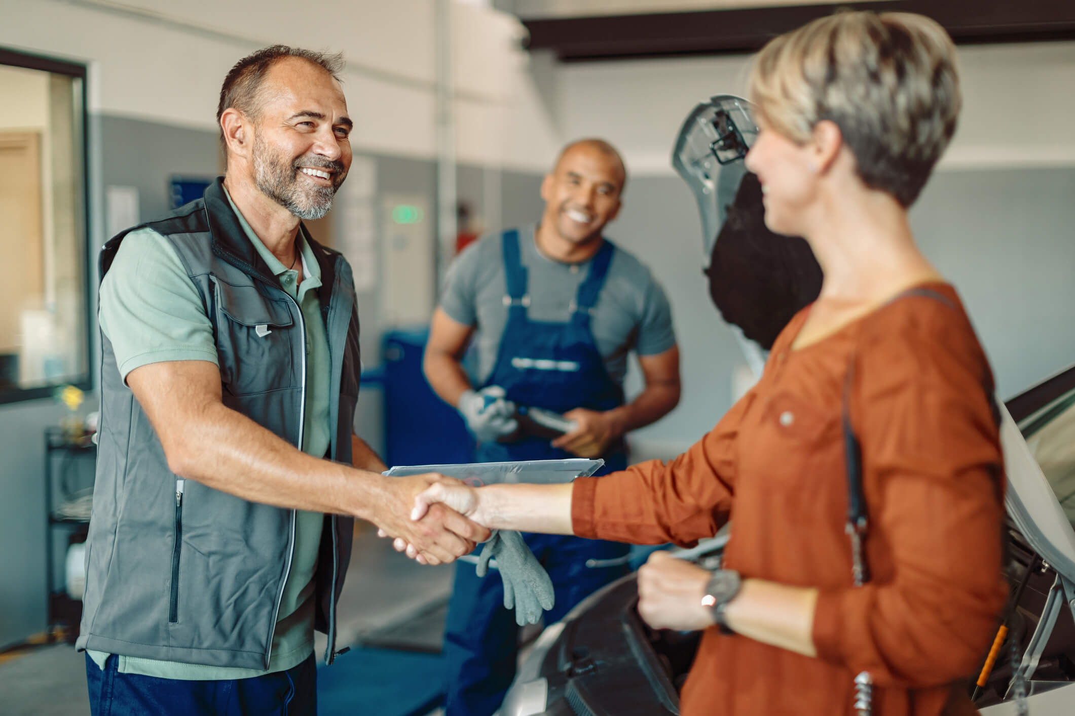 Auto repair person greeting his customer while working in an auto shop