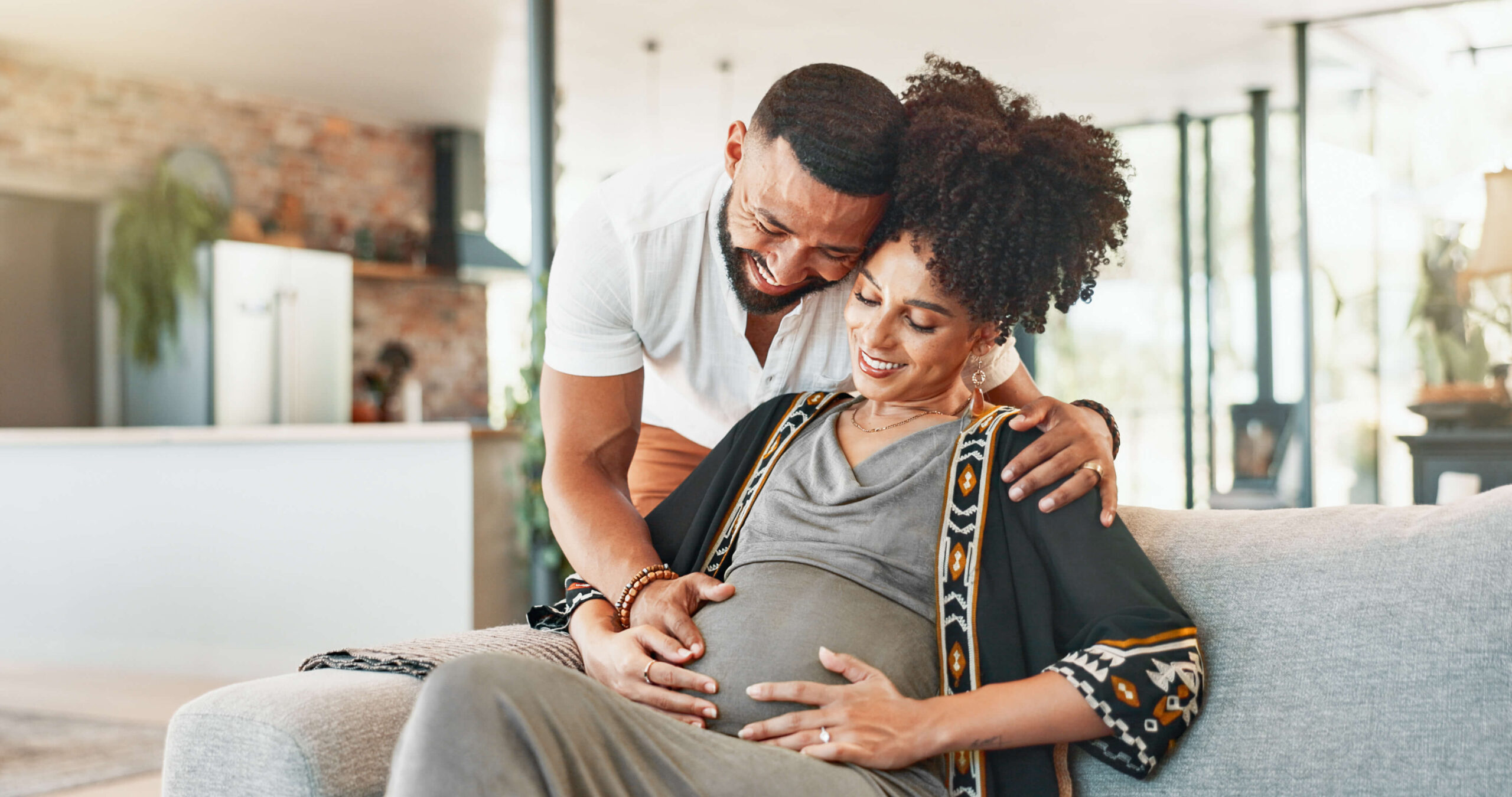 Pregnant, couple and woman on couch with bonding, tummy touch and support with maternity and motherhood. Future parents and affection on sofa with healthy pregnancy, embrace and excited for baby