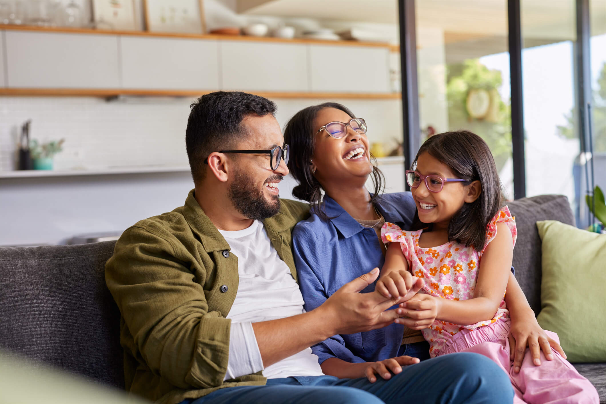 Parents with child smiling on a couch